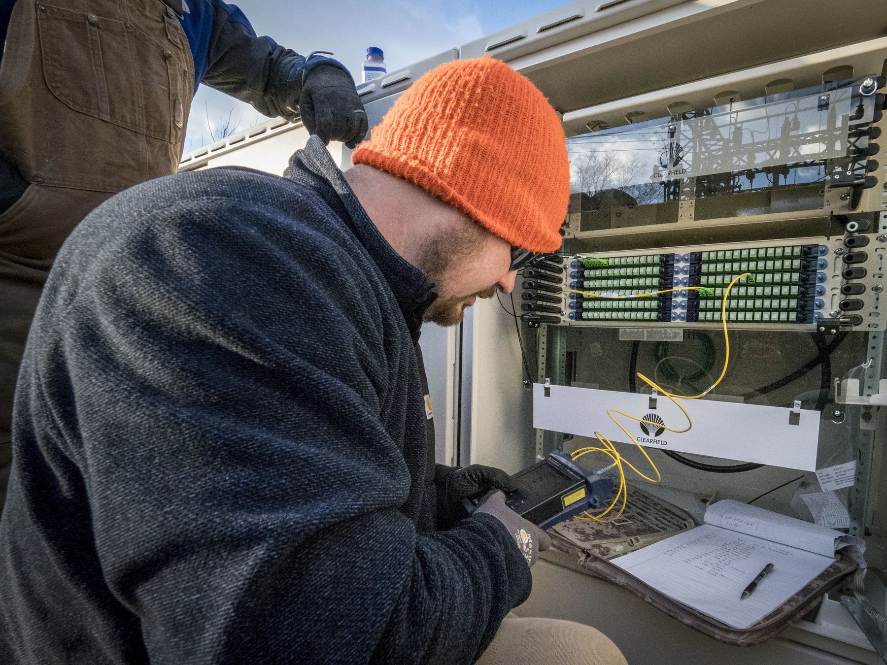 Technician testing fiber connections at an outdoor patch panel
